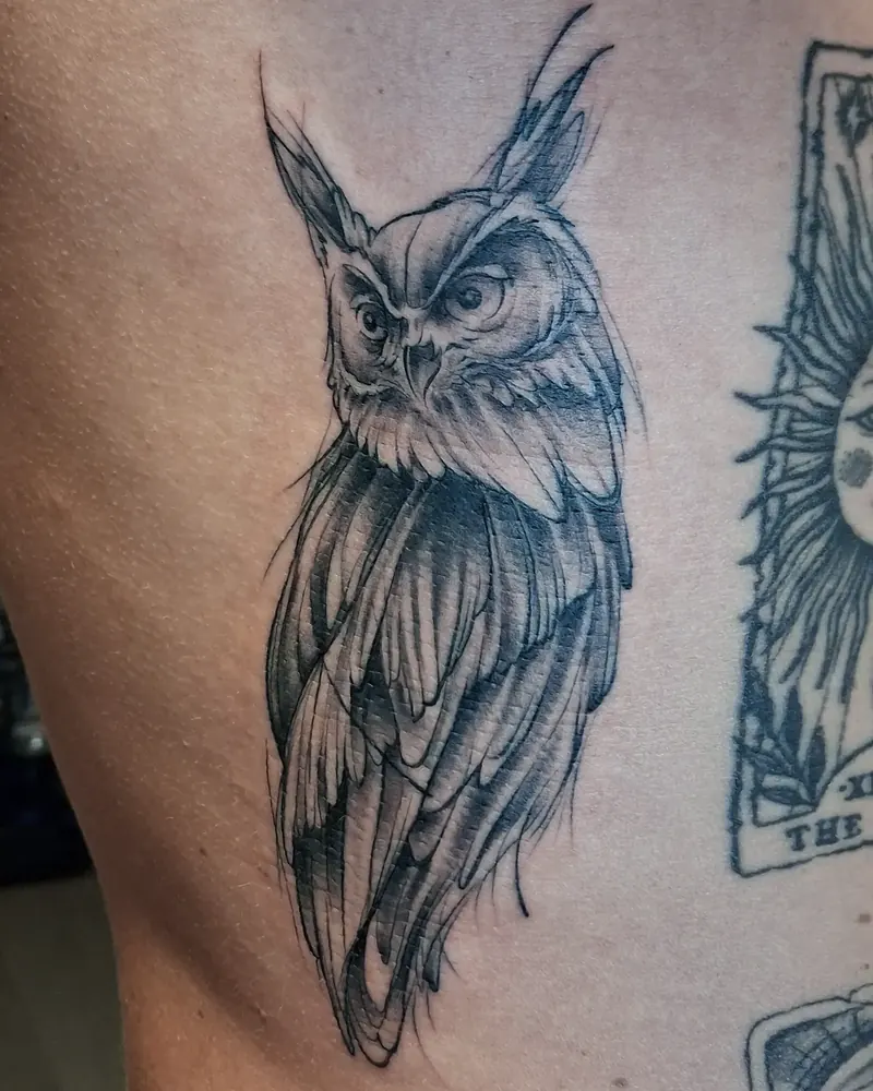 Black and grey ugle tatovert på ribbeina